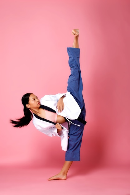 Fitnessmädchen, Frau kann Konzept machen. In voller Länge 12 Jahre alte Athletin trägt pastellfarbene Sportbekleidung und übt High Kick Karate, rosa Hintergrund, Kopierraum