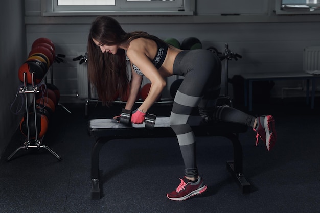 Fitnessmädchen führen Übung mit Hanteln auf dem breitesten Rückenmuskel durch.