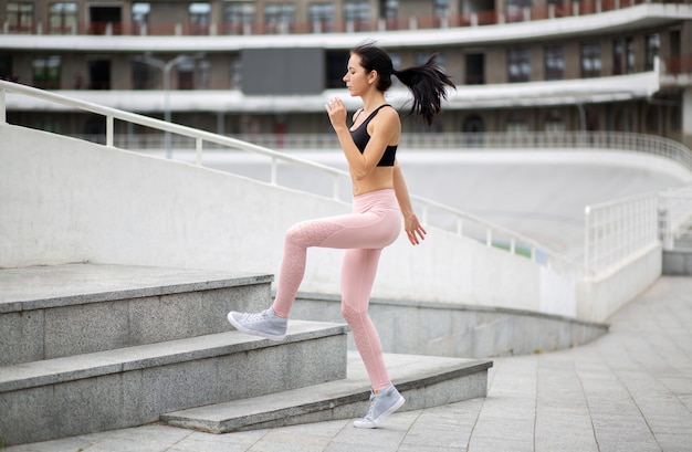 Fitnessmädchen trägt Sportkleidung, die während ihres morgendlichen Trainings auf Treppen springt. Freiraum