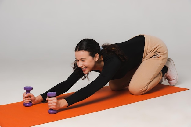 Fitnessmodel trainiert mit Hanteln und trinkt Wasser aus einer Sportflasche