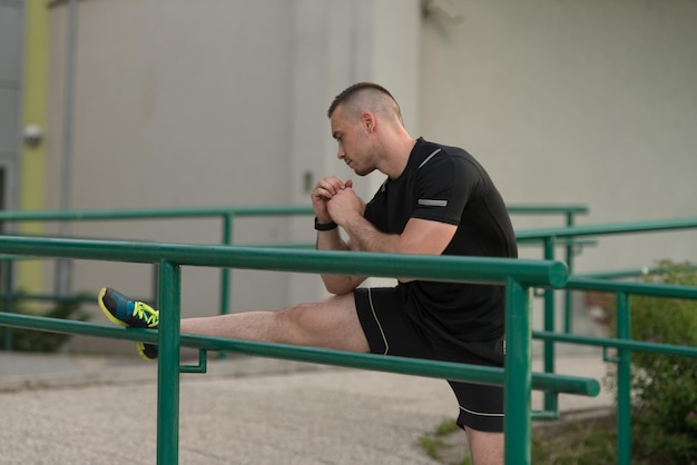 Fitnesstrainer Portrat im Freien, der Dehnungsübungen macht