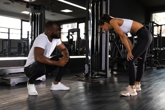 Fitnesstrainer trainiert mit seinem Kunden im Fitnessstudio