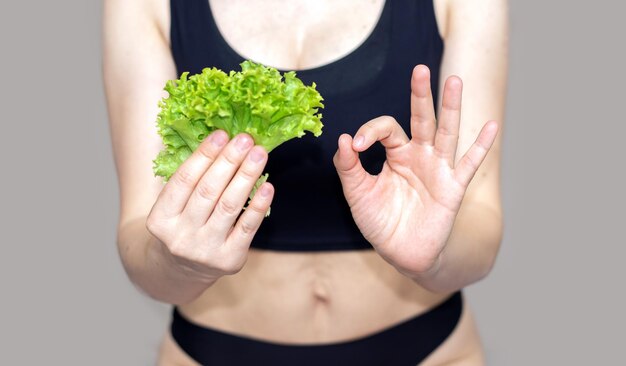 Fitslimsexy Mädchen mit grünem Salat Salatblatt mit Unterwäsche oder in der Hand Finger Daumen hoch gehalten