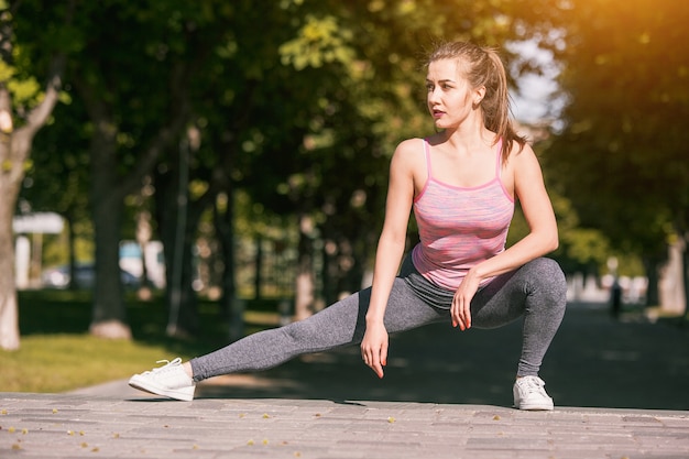 Fitte Fitnessfrau macht Dehnübungen im Freien im Park