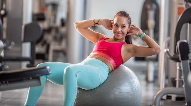 Fitte Frau, die im Fitnessstudio trainiert und Crunches auf einem Gymnastikball macht.