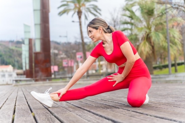 Fitte Frau in roter Kleidung beim Stretching in einem Stadtpark im Frühjahr Fitness