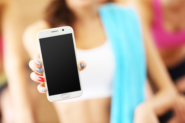 Fitte Frau mit Smartphone im Fitnessstudio