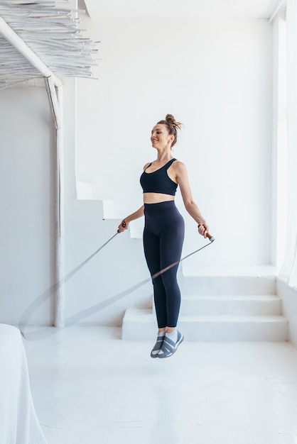 Fitte Frau mit Springseil zu Hause beim Überspringen des Trainings.