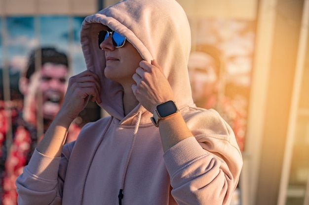 Fitte Frau mit tragbarer Smartwatch-Technologie, Sport-Smartwatch auf Fitnesslaufspaziergang draußen. Mädchen im rosa Hoodie beim Training im Freien