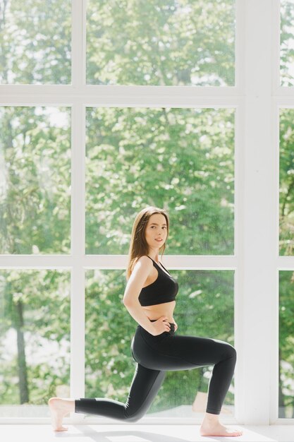 Fitte Frau posiert Yoga im Studio über Panoramafenster