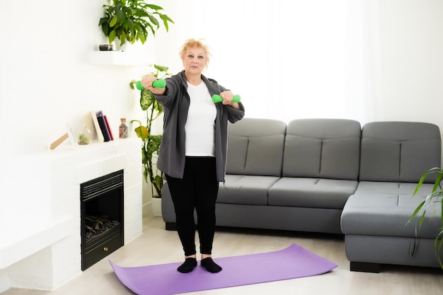 Fitte, glückliche Seniorin, die Dehnübungen auf ihrer Yogamatte macht.