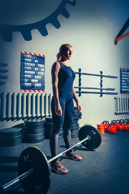 Fitte junge Frau, die Hanteln hebt, die in einem Fitnessstudio trainieren