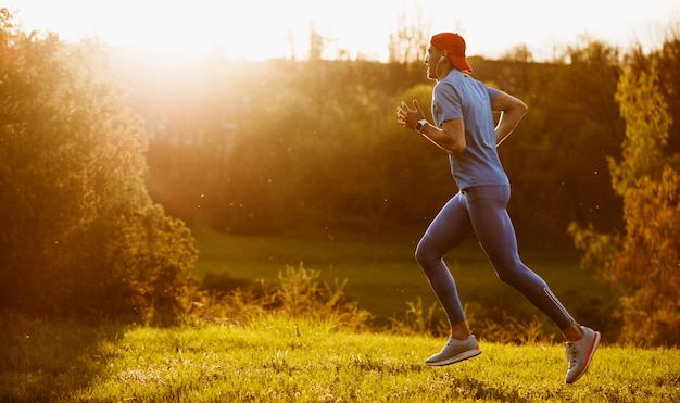 Fitter junger männlicher Jogger, der im Park bei Sonnenuntergang trainiert Handosme Athlet Läufer läuft und sprintet im Freien und bereitet sich auf Marathon in den Bergen vor Sport- und Menschenkonzept