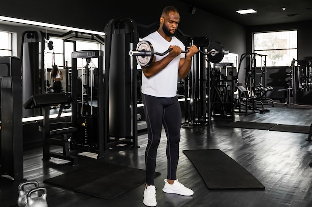 Fitter und muskulöser afrikanischer Mann, der im Fitnessstudio schwere Langhantelgewichte hebt