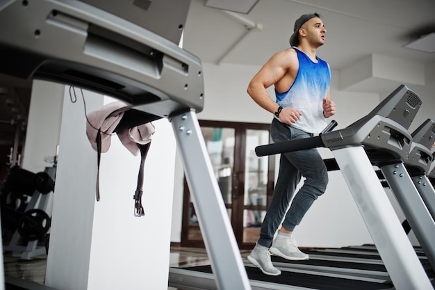 Fitter und muskulöser arabischer Mann, der im Fitnessstudio auf dem Laufband läuft