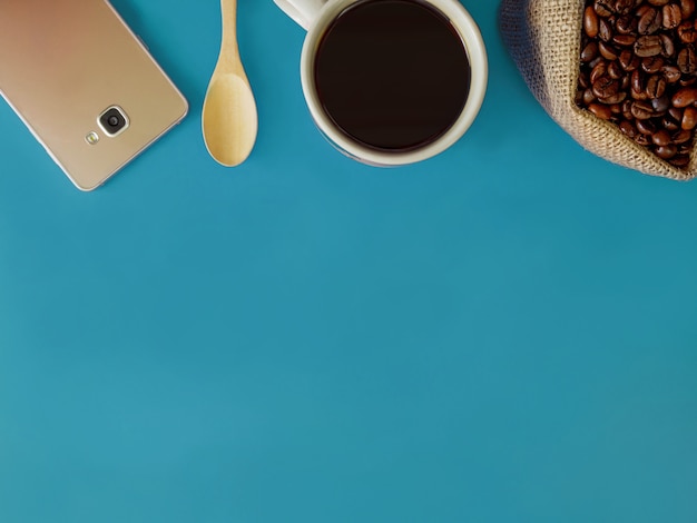 Flach legen Sie eine Tasse Kaffee und Smartphone auf blauem Schreibtisch mit Kopienraum