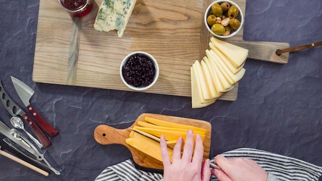 Flach liegen. Anrichten von Gourmet-Käse, Crackern und Früchten auf einem Brett für ein großes Käsebrett.