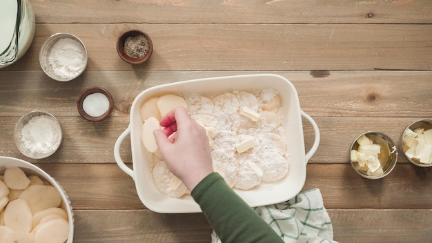 Flach liegen. Überbackene Kartoffeln in einer Auflaufform aus weißer Keramik zubereiten.