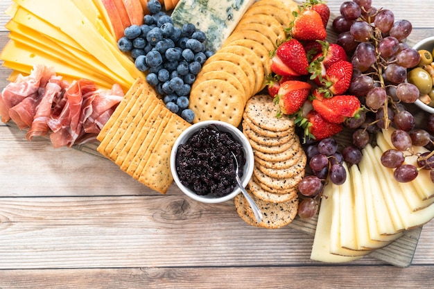 Flach liegen. Gourmet-Käse, Cracker und Obst auf einem Holzbrett dienten als Vorspeise.