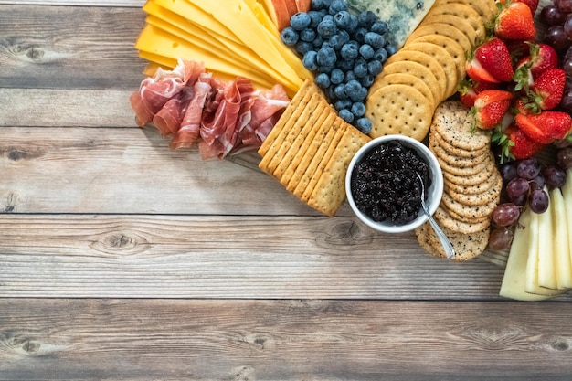 Flach liegen. Gourmet-Käse, Cracker und Obst auf einem Holzbrett dienten als Vorspeise.