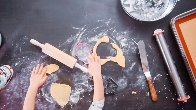 Flach liegen. Kleines Mädchen, das Zuckerschädelkekse für Dia de los Muertos-Urlaub backt.