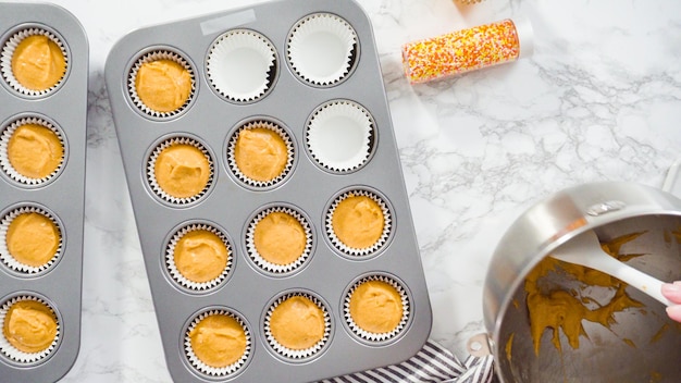 Flach liegen. Kürbisgewürz-Cupcake-Teig mit einer Teigschaufel in eine Cupcake-Pfanne mit Auskleidungen schöpfen.