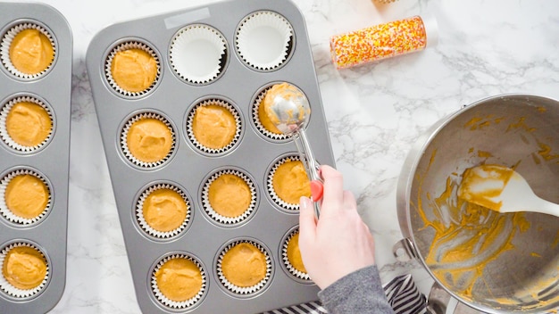 Flach liegen. Kürbisgewürz-Cupcake-Teig mit einer Teigschaufel in eine Cupcake-Pfanne mit Auskleidungen schöpfen.