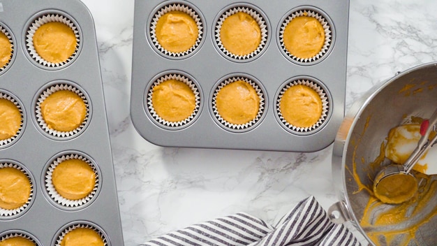 Flach liegen. Kürbisgewürz-Cupcake-Teig mit einer Teigschaufel in eine Cupcake-Pfanne mit Auskleidungen schöpfen.