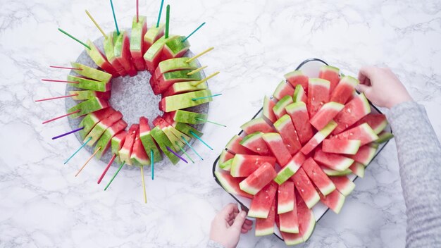 Flach liegen. Rote Wassermelone auf einem weißen Schneidebrett in kleine Stücke schneiden.