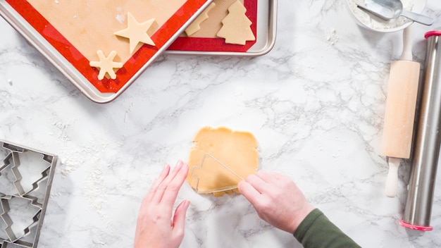 Flach liegen. Schritt für Schritt. Ausschneiden von Formen mit Weihnachtskeksausstecher aus Zuckerplätzchenteig.