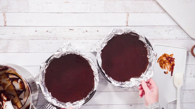 Flach liegen. Schritt für Schritt. Gießen Sie den geschmolzenen Teig in Backformen, die mit Kochfolie ausgelegt sind, um einfachen Schokoladenfondant herzustellen.