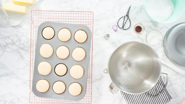 Flach liegen. Schritt für Schritt. Kühlen von frisch gebackenen Vanille-Cupcakes auf Drahtkühlgestell.