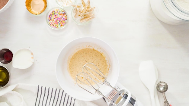 Flach liegen. Schritt für Schritt. Mischen Sie die Zutaten in einer weißen Rührschüssel, um Einhorn-Schokoladen-Cupcakes mit Buttercreme-Zuckerguss zuzubereiten.