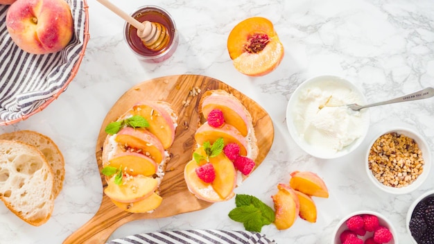 Flach liegen. Schritt für Schritt. Ricotta-Toasts mit Bio-Pfirsichen und Beeren zubereiten.