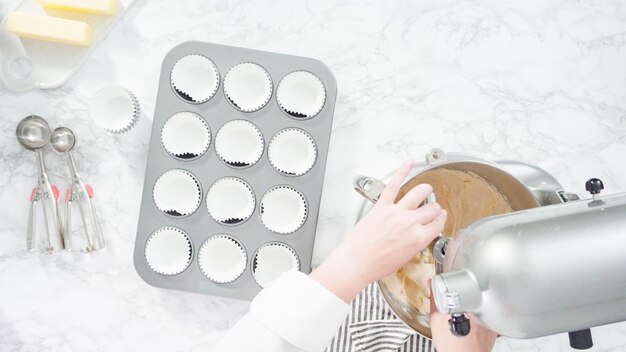 Flach liegen. Schritt für Schritt. Schaufeln Sie den Teig mit einem Teiglöffel in eine Cupcake-Form, die mit Cupcake-Förmchen ausgelegt ist.