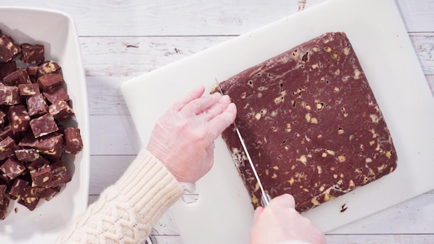 Flach liegen. Schritt für Schritt. Schneiden von hausgemachtem Macadamia-Fudge auf einem weißen Schneidebrett.