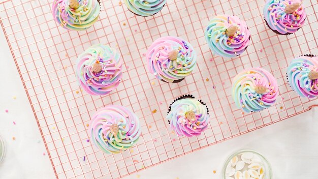 Flach liegen. Schritt für Schritt. Zuckerguss-Einhorn-Schokoladen-Cupcakes mit regenbogenfarbenem Buttercreme-Zuckerguss.