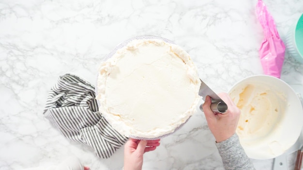 Flach liegen. Schritt für Schritt. Zuckerguss runder Funfetti-Kuchen mit weißem italienischem Buttercreme-Zuckerguss.