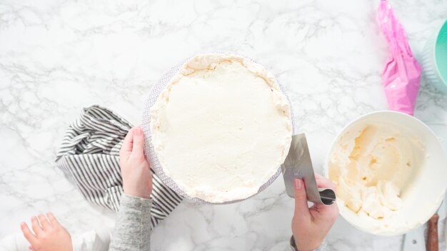 Flach liegen. Schritt für Schritt. Zuckerguss runder Funfetti-Kuchen mit weißem italienischem Buttercreme-Zuckerguss.