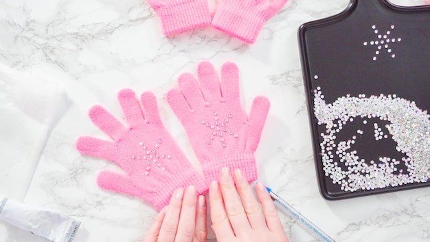 Flach liegen. Strassrosa Kinderhandschuhe mit Schneeflockenformen.