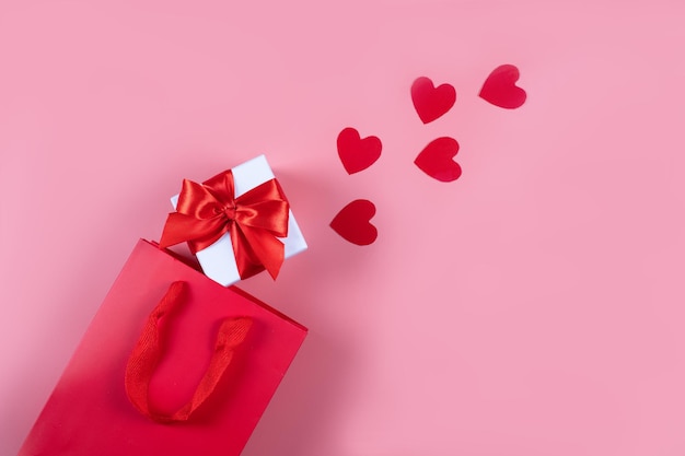 Foto flach liegen. verpackungen für einkäufe, geschenke und pakete auf rosafarbenem hintergrund. das konzept der lieferung von geschenken und paketen für die feiertage valentinstag, angenehme überraschungen. einkaufen, verkauf, promotion.