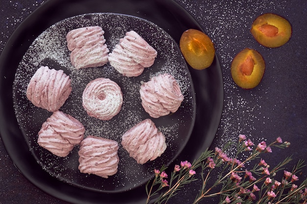 Flach liegend mit einem Teller hausgemachter Marshmallows aus schwarzen Pflaumen