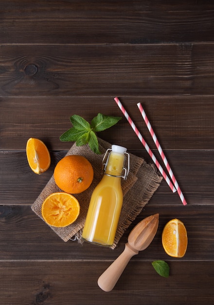 flach mit frisch gepresstem Orangensaft mit Minzflasche auf Holzhintergrund