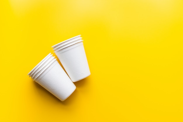 Flache Auflage von nachhaltigen Produkten, Papierglas auf gelb