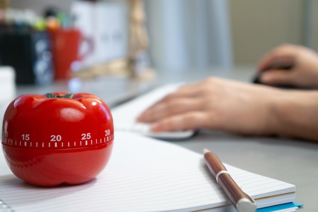 Flache Aufnahme eines tomatenförmigen Timers und eines Notizbuchs auf dem Tisch