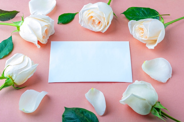 Flache Blumenkomposition für Ihren Schriftzug. Rahmen aus weißen Rosenblüten auf rosa Hintergrund. Einladungsgrußkarte.