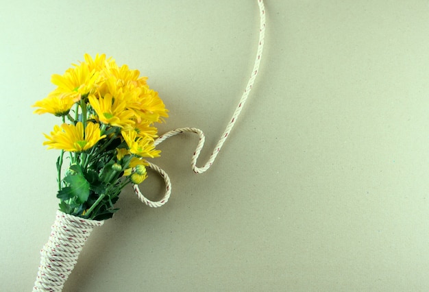 Flache blumenstrauß gelbe mütter oder chrysanthemenblumen, die mit seil auf grauem hintergrund binden