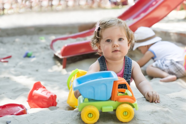 Flache Fokusaufnahme eines süßen kleinen Mädchens, das im Sandkasten spielt