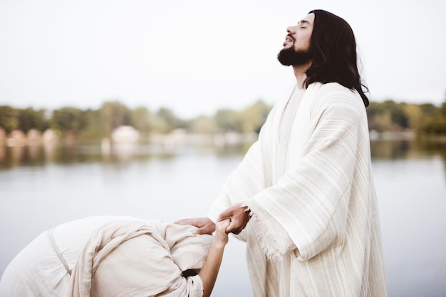 Flache Fokusaufnahme von Jesus Christus, der eine Frau mit seiner Hand auf ihrem Kopf heilt