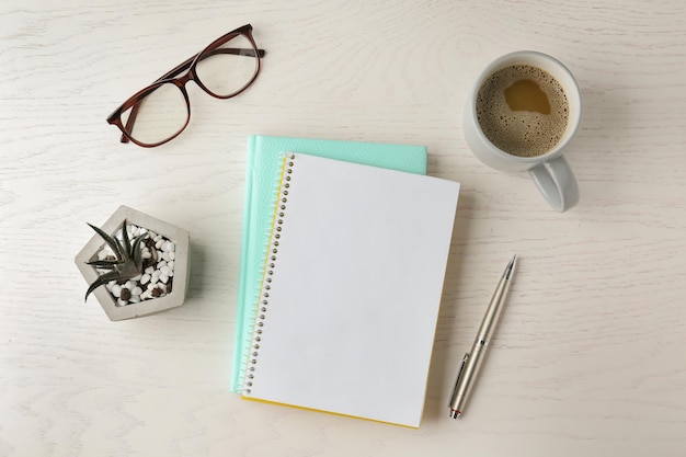 Flache Komposition mit Büromaterial und einer Tasse Kaffee auf weißem Holztisch Raum für Design